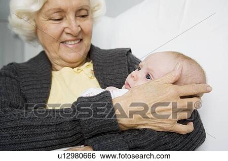 Stock Photograph - A grandmother holding her new grandchild. Fotosearch