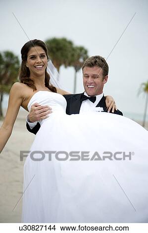 A groom carrying his bride View Large Photo Image Picture - A groom carrying his bride. Fotosearch