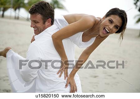 Stock Image - A groom carrying his bride. Fotosearch