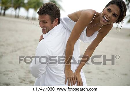 Stock Image - A groom carrying his bride. Fotosearch