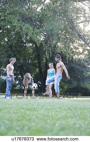 Stock Image - A group of teenage friends playing with a football. Fotosearch