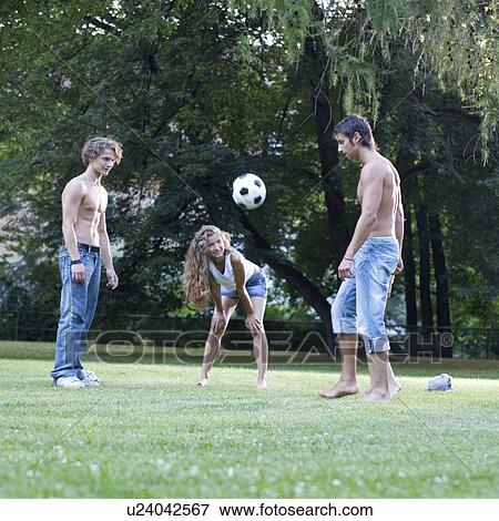 Stock Photo - A group of teenage friends playing with a football. Fotosearch