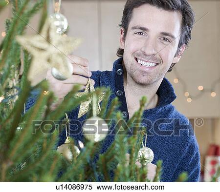 Stock Photography - A man decorating the Christmas tree. Fotosearch