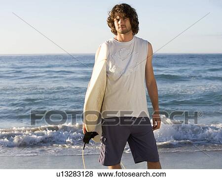 A man holding a surfboard View Large Photo Image Stock Photo - A man holding a surfboard. Fotosearch
