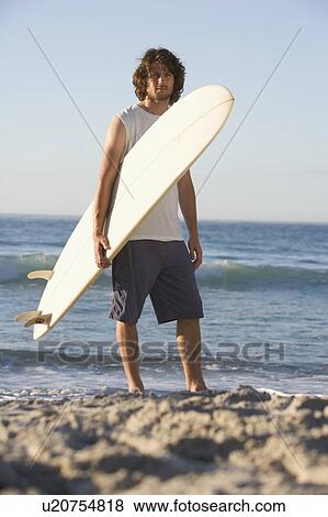 Stock Photo - A man holding a surfboard. Fotosearch