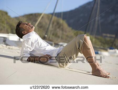 A man laying on a beach View Large Photo Image Stock Image - A man laying on a beach. Fotosearch
