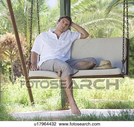 Stock Image - A man relaxing on a swing. Fotosearch