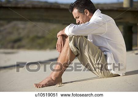 A man sitting on a beach View Large Photo Image Stock Image - A man sitting on a beach. Fotosearch