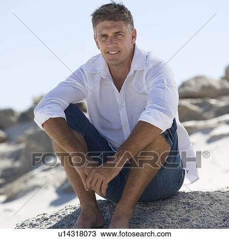 Stock Image - A man sitting on rocks. Fotosearch