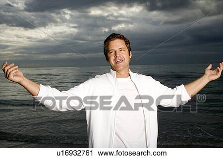 Stock Image - A man standing on a stormy beach. Fotosearch