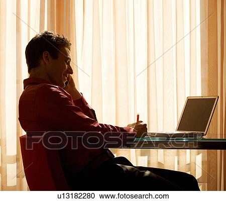 Stock Image - A man using a laptop at a desk. Fotosearch