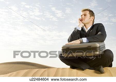 A man with a suitcase sitting in a desert View Large Photo Image Picture - A man with a suitcase sitting in a desert. Fotosearch