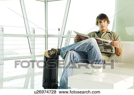 Stock Photo - A man with a suitcase waiting in a lobby. Fotosearch