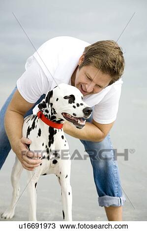 Stock Image - A man with his dog on a beach. Fotosearch