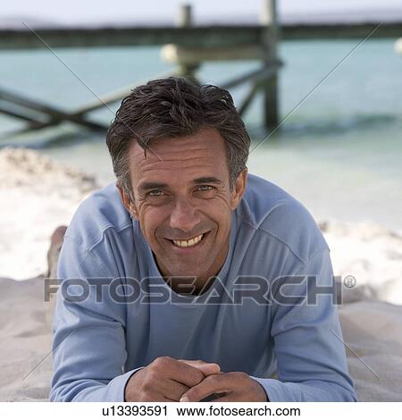 Stock Image - A mature man laying on a beach. Fotosearch