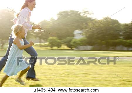 A mother and her young daughter running in a park View Large Photo Image Picture - A mother and her young daughter running in a park. Fotosearch
