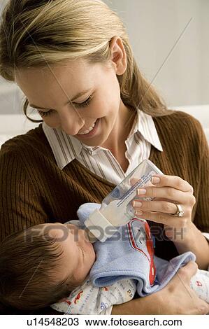 Stock Image - A mother bottle feeding her baby. Fotosearch