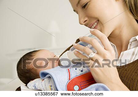 Stock Photo - A mother bottle feeding her baby. Fotosearch