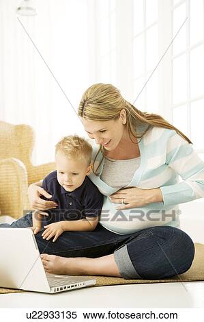 Stock Photography - A pregnant woman and her son using a laptop. Fotosearch
