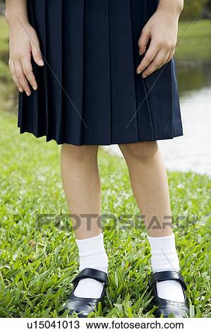 Stock Image - A schoolgirl standing by a pond. Fotosearch