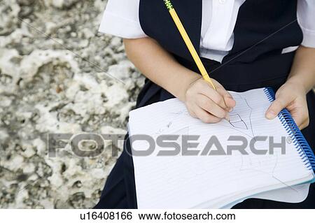 Stock Photograph - A schoolgirl writing in a notebook. Fotosearch