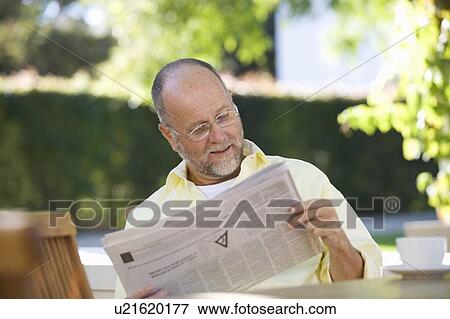 Stock Photo - A senior man reading the paper in the garden. Fotosearch