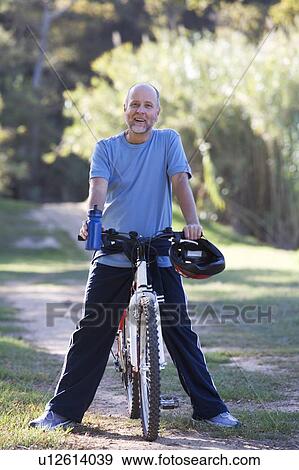 Stock Photo - A senior man resting on a bicycle. Fotosearch