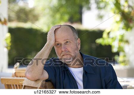 Stock Photo - A senior man sitting in a garden. Fotosearch