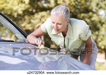 Picture - A senior woman cleaning her car. Fotosearch
