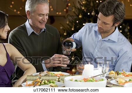 Stock Image - A son pouring his father a glass of wine. Fotosearch