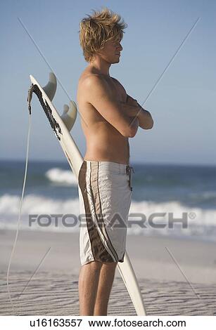 Stock Photo - A surfer standing on a beach. Fotosearch