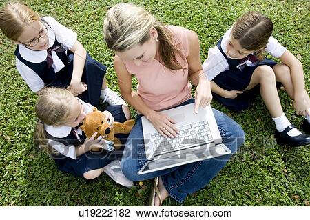 Stock Image - A teacher and children using a laptop outside. Fotosearch