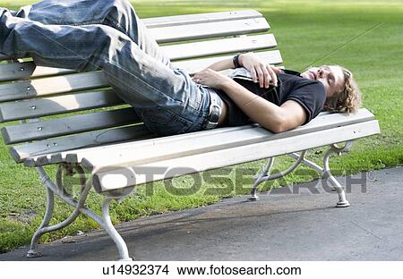A teenage boy laying on a park bench View Large Photo Image Picture - A teenage boy laying on a park bench. Fotosearch