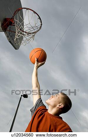 Stock Image - A teenage boy playing basketball. Fotosearch