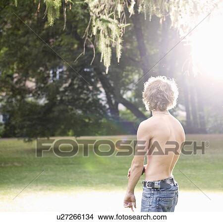 Picture - A teenage boy standing in a park. Fotosearch