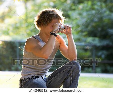Stock Image - A teenage boy taking a photo. Fotosearch