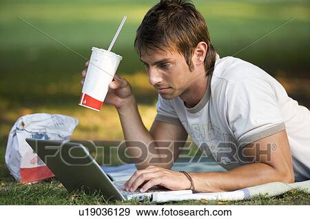 A teenage boy working on a laptop in a park View Large Photo Image Stock Photo - A teenage boy working on a laptop in a park. Fotosearch