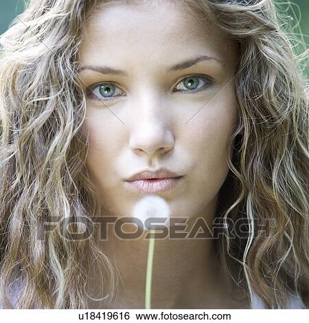 Stock Photograph - A teenage girl blowing on a dandelion seedhead. Fotosearch