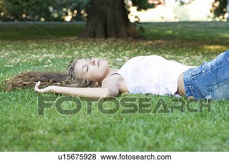 Stock Photo - A teenage girl laying in a park. Fotosearch