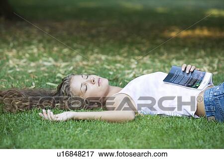 Stock Photo - A teenage girl laying in a park. Fotosearch