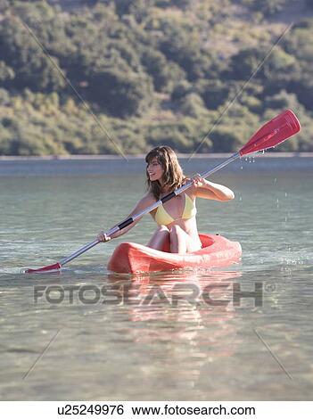 Stock Photograph - A woman canoeing on a lake. Fotosearch