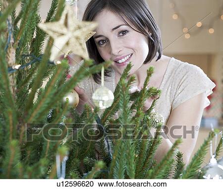 Stock Image - A woman decorating a Christmas tree. Fotosearch