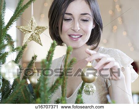 Stock Image - A woman decorating a Christmas tree. Fotosearch
