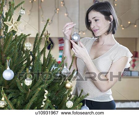 Stock Photo - A woman decorating a Christmas tree. Fotosearch