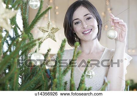 Stock Photograph - A woman decorating a Christmas tree. Fotosearch
