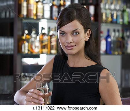 Stock Image - A woman drinking champagne in a bar. Fotosearch