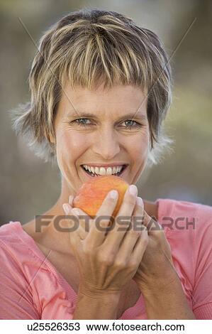 Stock Image - A woman eating a peach. Fotosearch