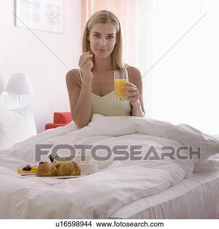 Picture - A woman having breakfast in bed. Fotosearch