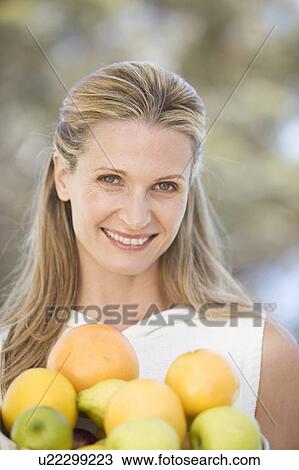 Stock Image - A woman holding a bowl of fruit. Fotosearch