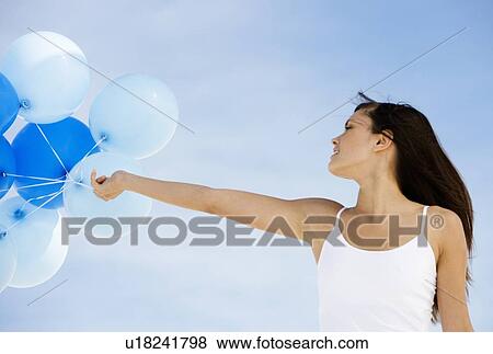 A woman holding a bunch of balloons View Large Photo Image Stock Photo - A woman holding a bunch of balloons. Fotosearch